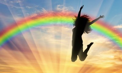 Happy woman jumping near rainbow